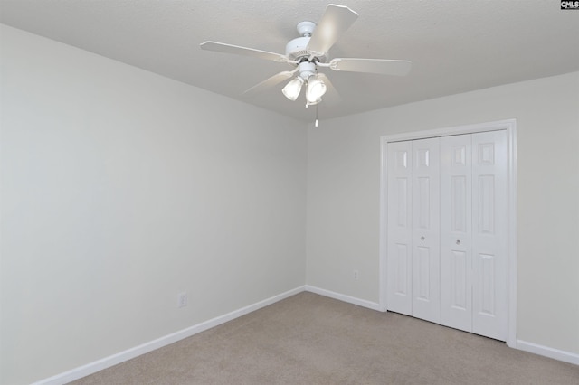 unfurnished bedroom featuring light carpet, a closet, a ceiling fan, and baseboards