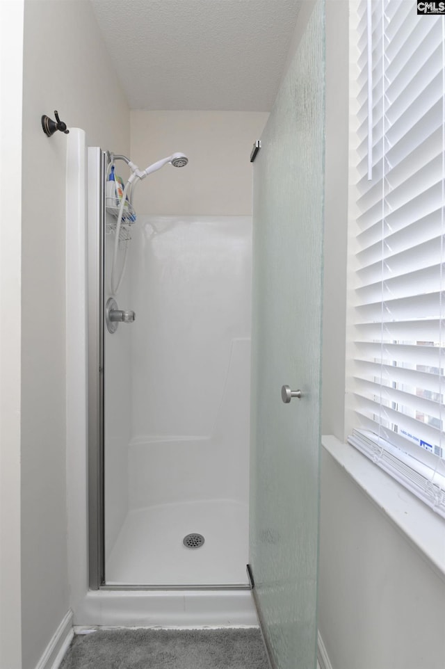 full bath featuring a shower stall, baseboards, and a textured ceiling