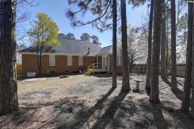 back of property featuring an outdoor fire pit, a shingled roof, crawl space, fence, and brick siding