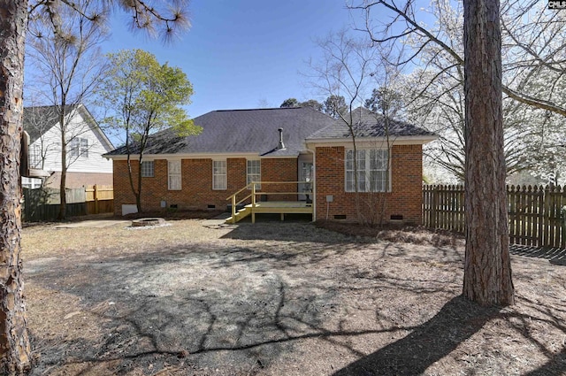 rear view of house featuring an outdoor fire pit, brick siding, fence, roof with shingles, and crawl space