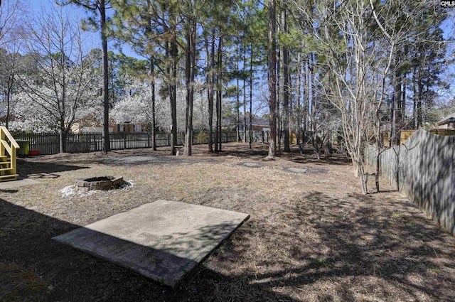 view of yard with a fenced backyard and a fire pit