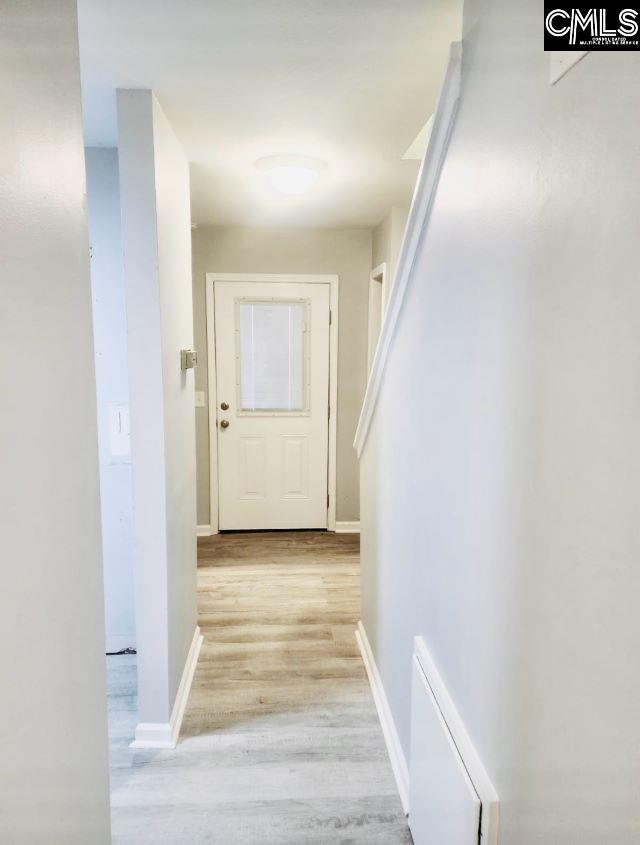 hallway featuring light wood-style flooring and baseboards