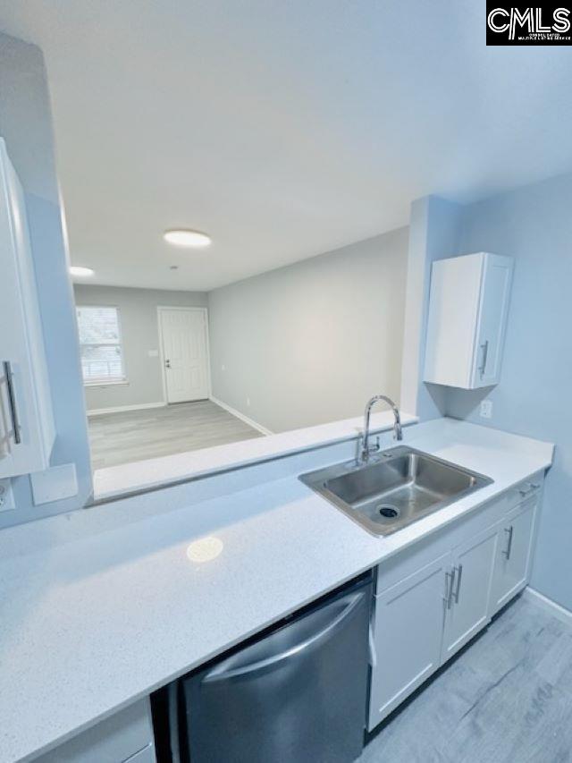 kitchen with dishwasher, light countertops, a sink, and white cabinetry