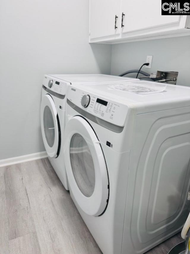 washroom featuring cabinet space, light wood-style flooring, baseboards, and independent washer and dryer