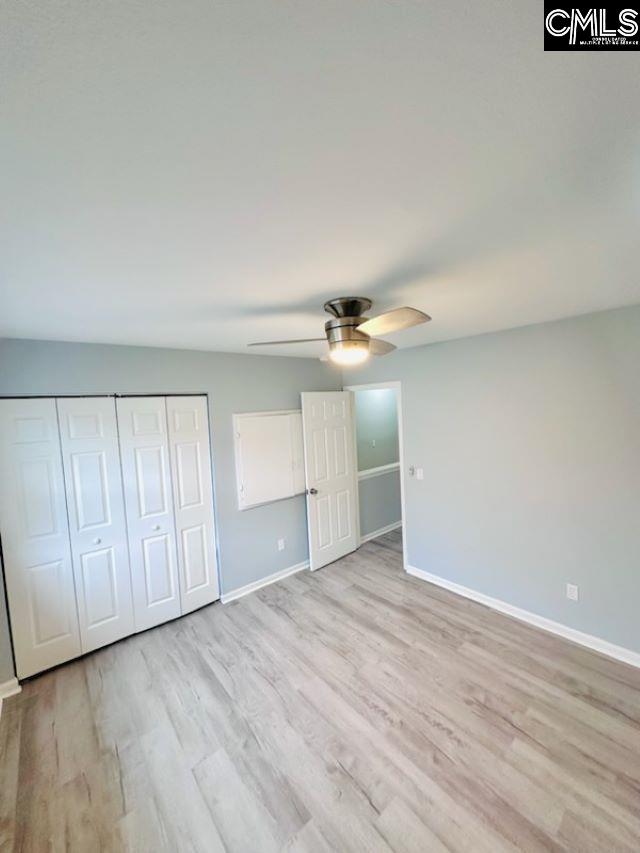 unfurnished bedroom featuring light wood-style floors, a closet, ceiling fan, and baseboards