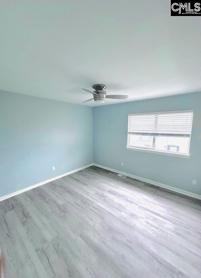 empty room featuring ceiling fan, baseboards, and wood finished floors