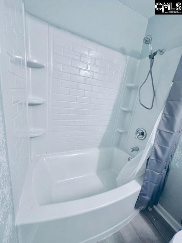 bathroom with wood finished floors and shower / bathtub combination with curtain