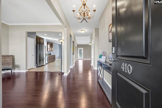 corridor with light wood-type flooring, an inviting chandelier, baseboards, and ornamental molding