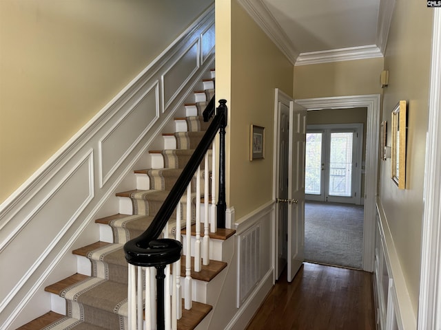 stairs with a decorative wall, a wainscoted wall, wood finished floors, visible vents, and ornamental molding