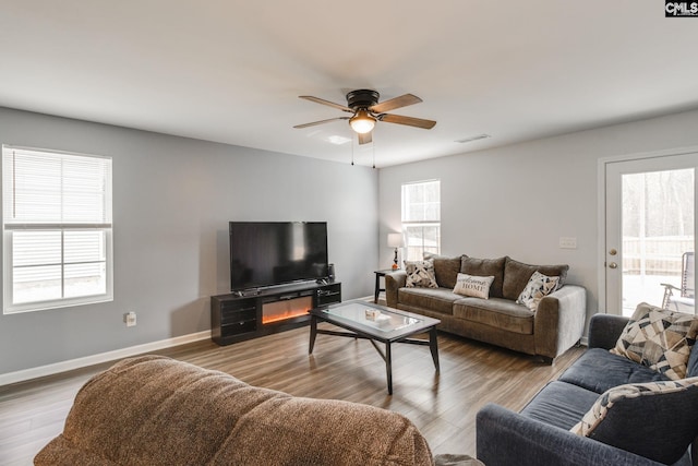 living room featuring a ceiling fan, baseboards, visible vents, and wood finished floors