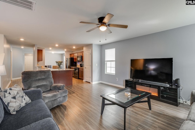 living room featuring ceiling fan, light wood-style flooring, recessed lighting, visible vents, and baseboards