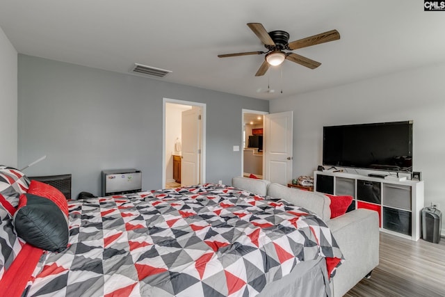 bedroom featuring a ceiling fan, connected bathroom, visible vents, and wood finished floors