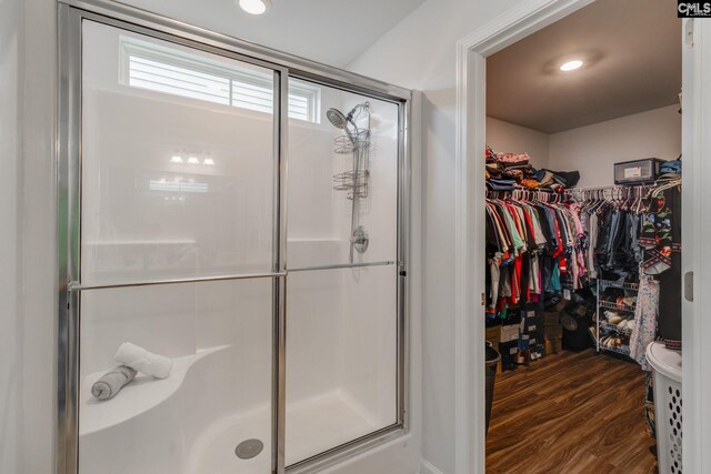 full bathroom with a stall shower, a walk in closet, recessed lighting, and wood finished floors