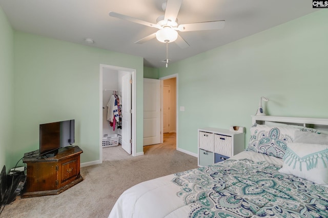 bedroom with a ceiling fan, carpet, a walk in closet, and baseboards