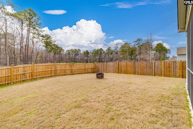 view of yard featuring a fenced backyard and a fire pit