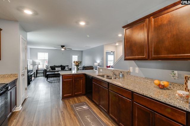 kitchen with dishwasher, light stone counters, open floor plan, wood finished floors, and a sink