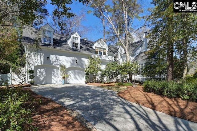 cape cod house with aphalt driveway, fence, and an attached garage