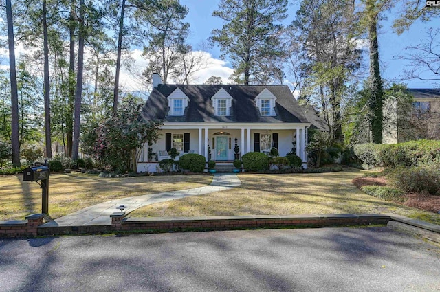 new england style home featuring covered porch and a front lawn