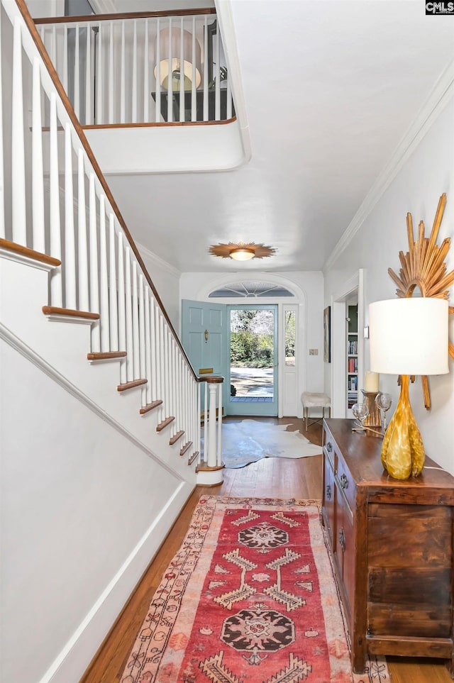 entryway with baseboards, stairs, ornamental molding, and wood finished floors