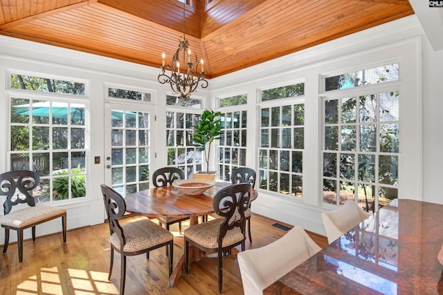 sunroom featuring a wealth of natural light, wood ceiling, a raised ceiling, and a notable chandelier