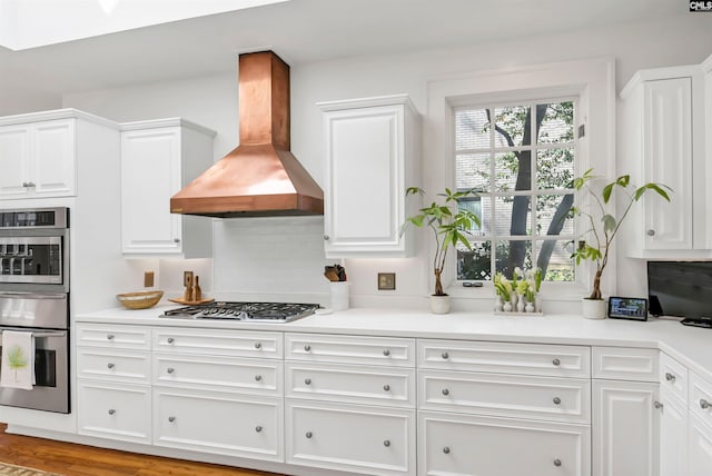 kitchen with gas cooktop, white cabinetry, and wall chimney exhaust hood