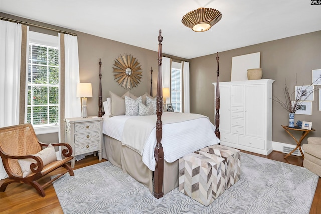 bedroom featuring multiple windows, wood finished floors, visible vents, and baseboards