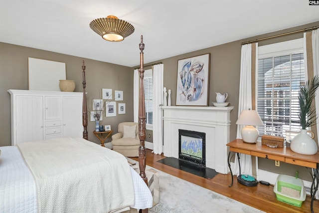 bedroom with a fireplace with flush hearth and wood finished floors