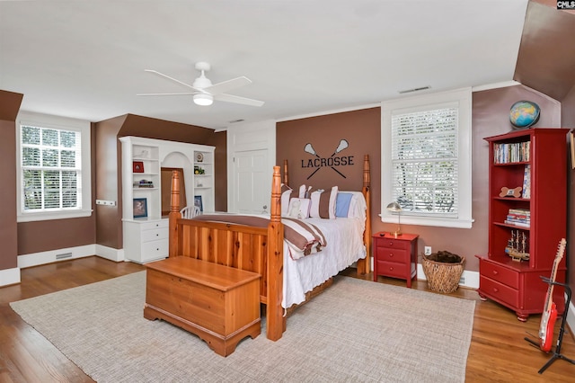 bedroom featuring ceiling fan, wood finished floors, visible vents, and baseboards