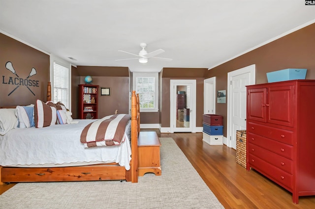 bedroom with ceiling fan, wood finished floors, visible vents, baseboards, and ornamental molding