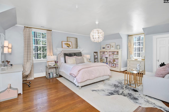 bedroom featuring lofted ceiling, a notable chandelier, baseboards, and wood finished floors