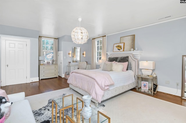 bedroom featuring baseboards, a notable chandelier, visible vents, and wood finished floors