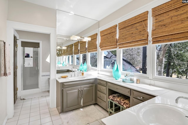 full bath with double vanity, tile patterned flooring, a sink, and a healthy amount of sunlight