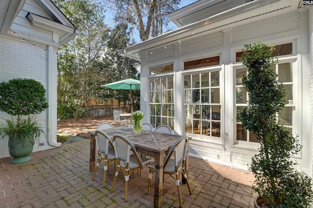 view of patio / terrace with outdoor dining space, fence, and a sunroom