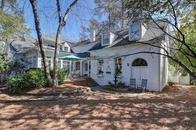 cape cod home with brick siding and a chimney