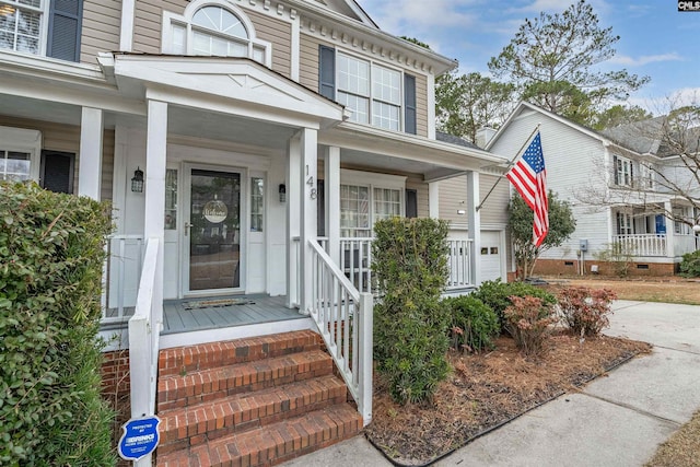 view of exterior entry featuring a porch and a garage