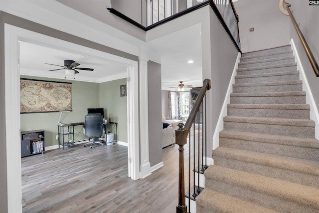 staircase with ornamental molding, a ceiling fan, baseboards, and wood finished floors