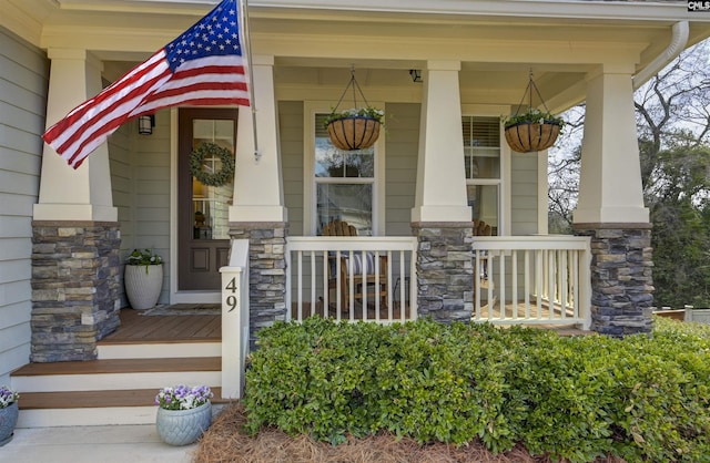 doorway to property with a porch and stone siding