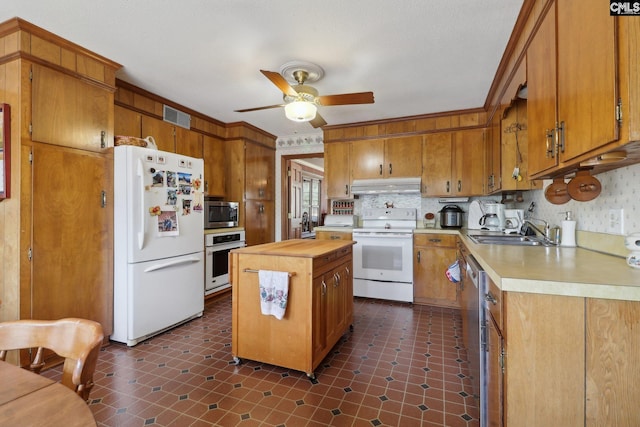 kitchen with under cabinet range hood, white appliances, butcher block counters, a sink, and visible vents