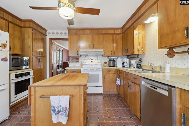 kitchen with a center island, stainless steel appliances, a sink, under cabinet range hood, and wallpapered walls