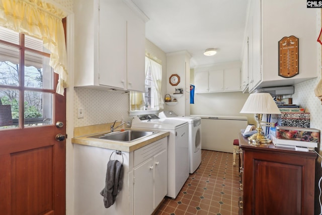 clothes washing area with washer and clothes dryer, a sink, cabinet space, and tile patterned floors