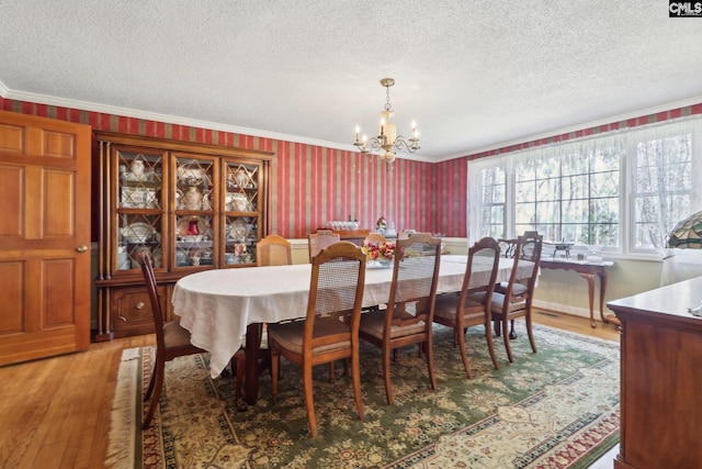 dining area featuring crown molding, light wood-style flooring, an inviting chandelier, a textured ceiling, and wallpapered walls