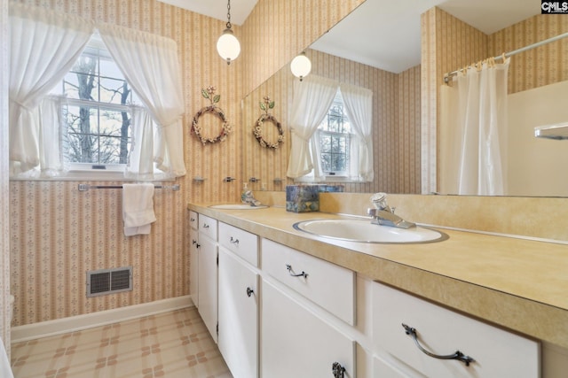 bathroom featuring double vanity, wallpapered walls, visible vents, and a sink