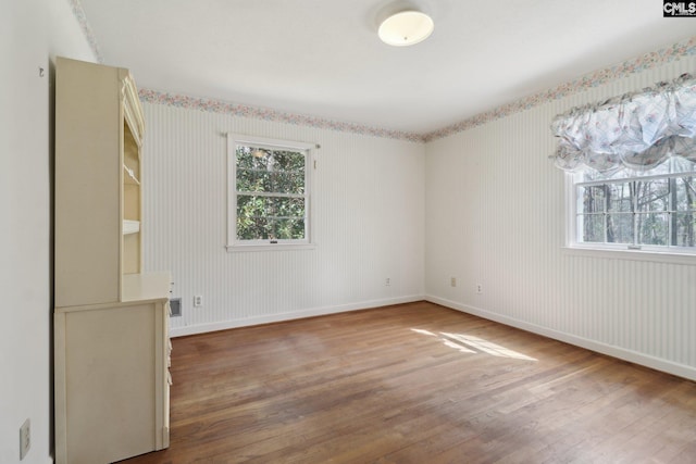 unfurnished room featuring a wealth of natural light, baseboards, and wood finished floors