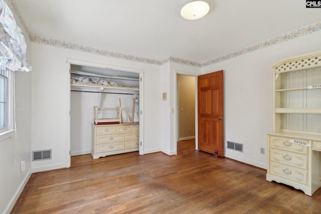 unfurnished bedroom featuring baseboards, a closet, visible vents, and hardwood / wood-style floors