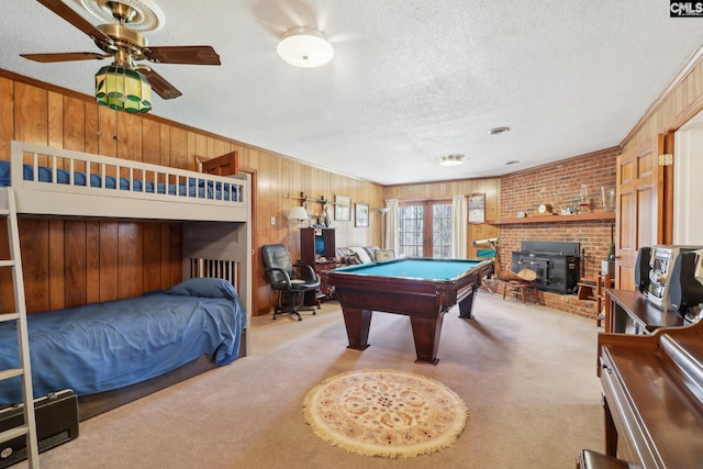 rec room with carpet, pool table, a wood stove, wood walls, and a textured ceiling