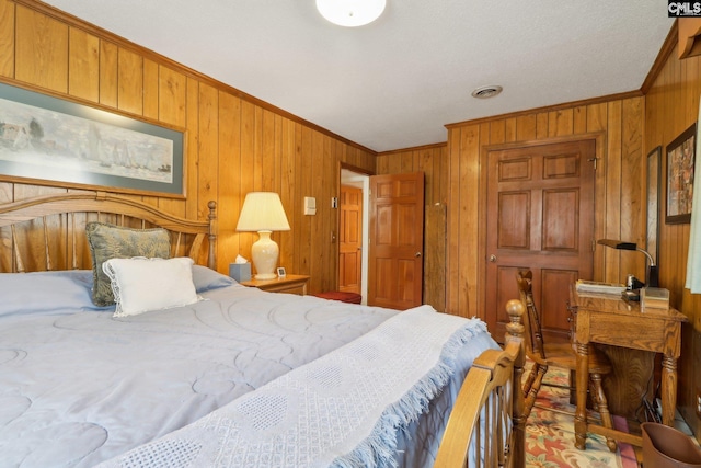 bedroom with wooden walls, visible vents, and crown molding