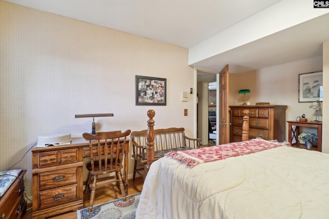 bedroom with wood finished floors and wallpapered walls