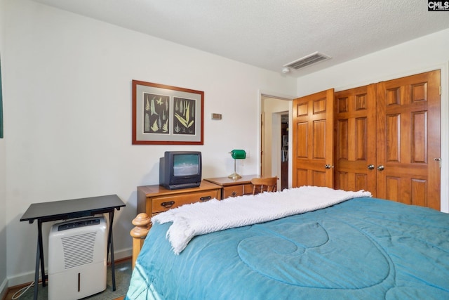 bedroom with a textured ceiling, visible vents, and baseboards