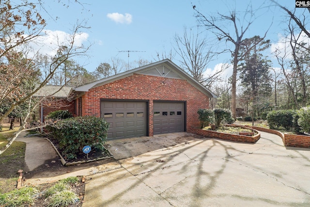 view of side of property featuring concrete driveway, brick siding, and an attached garage