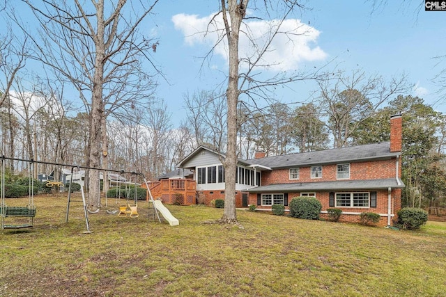 back of property with a sunroom, a chimney, a playground, and a yard